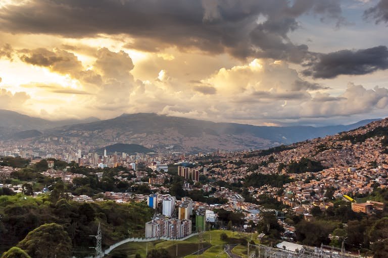 Breathtaking view of Medellin's skyline at sunset with dramatic clouds and vibrant colors.